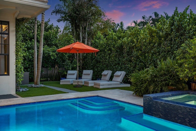 pool at dusk featuring fence, a patio, an in ground hot tub, and a fenced in pool