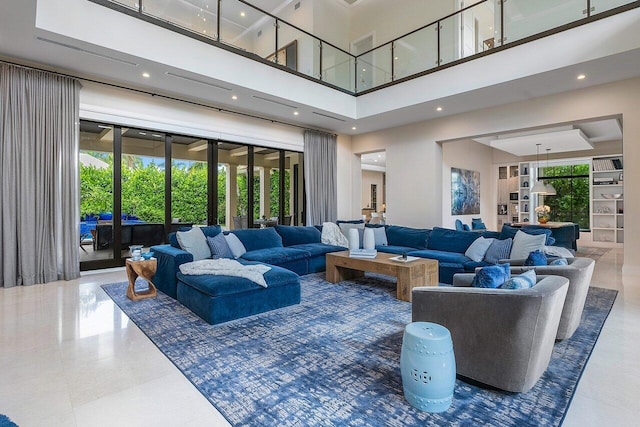 living room with plenty of natural light, visible vents, and a towering ceiling