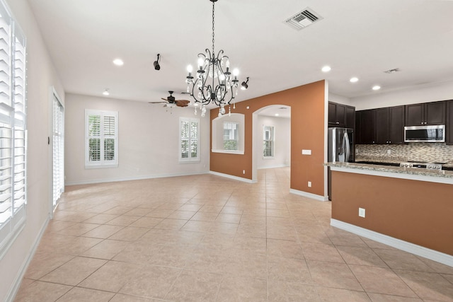 kitchen featuring tasteful backsplash, light tile patterned floors, light stone countertops, ceiling fan with notable chandelier, and stainless steel appliances