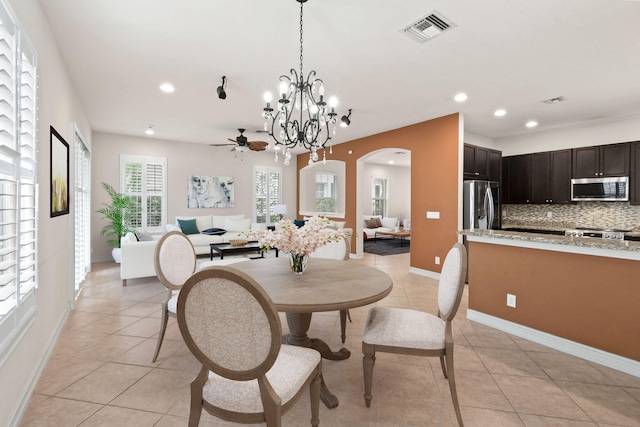 dining space with light tile patterned flooring and ceiling fan with notable chandelier