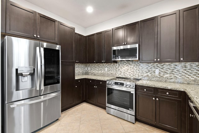 kitchen featuring decorative backsplash, dark brown cabinets, light stone countertops, light tile patterned floors, and appliances with stainless steel finishes