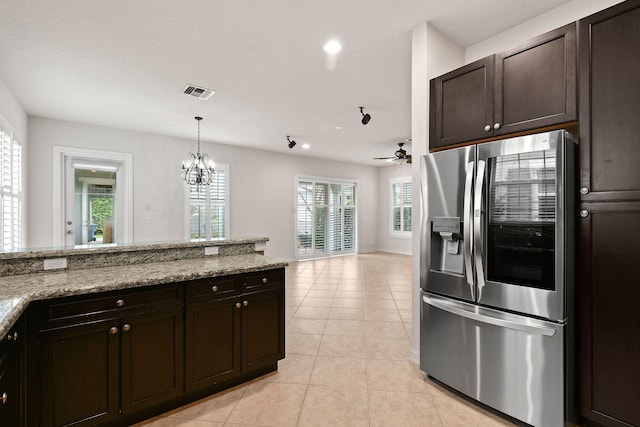 kitchen featuring light stone countertops, stainless steel fridge with ice dispenser, dark brown cabinets, and plenty of natural light