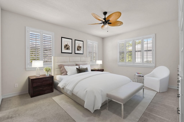 carpeted bedroom with a textured ceiling, multiple windows, and ceiling fan