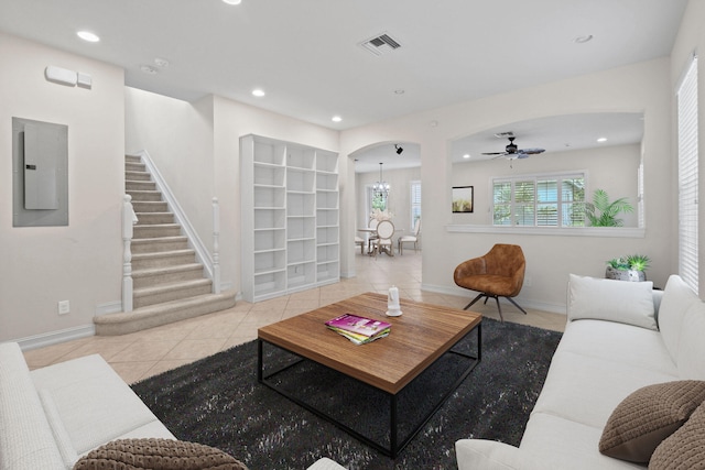 tiled living room with electric panel and ceiling fan with notable chandelier