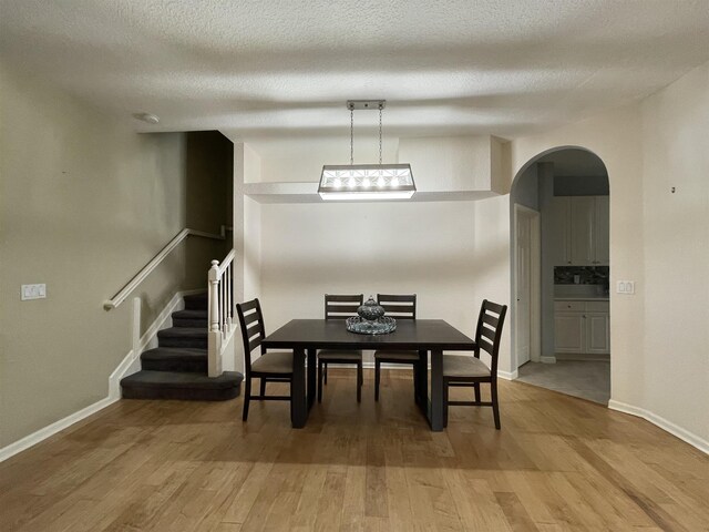 328 SE Bloxham Way, Stuart, FL 34997 - dining area featuring arched walkways, light wood finished floors, baseboards, stairs, and a textured ceiling