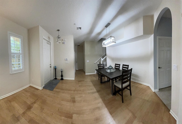 328 SE Bloxham Way, Stuart, FL 34997 - dining area with light wood-style flooring, stairway, baseboards, and arched walkways