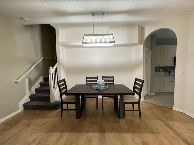 328 SE Bloxham Way, Stuart, FL 34997 - dining area with arched walkways, light wood-style floors, baseboards, and stairs
