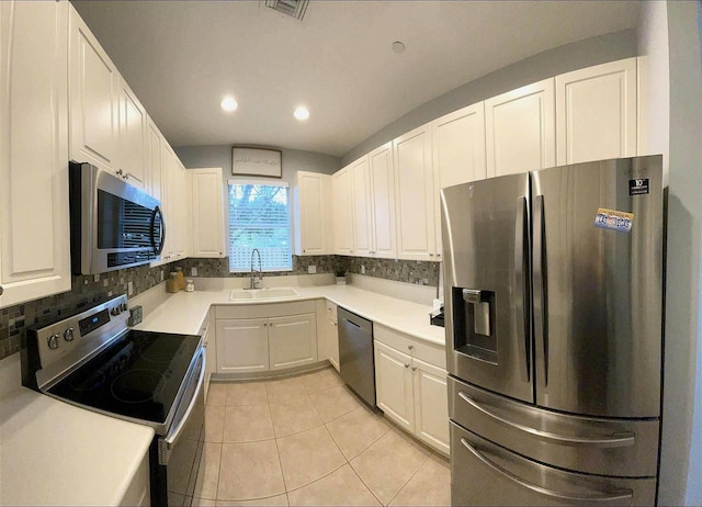 kitchen with tasteful backsplash, stainless steel appliances, sink, light tile patterned floors, and white cabinetry