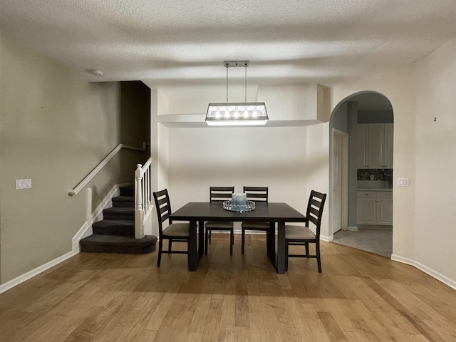 328 SE Bloxham Way, Stuart, FL 34997 - dining area with arched walkways, light wood-type flooring, baseboards, stairway, and a textured ceiling