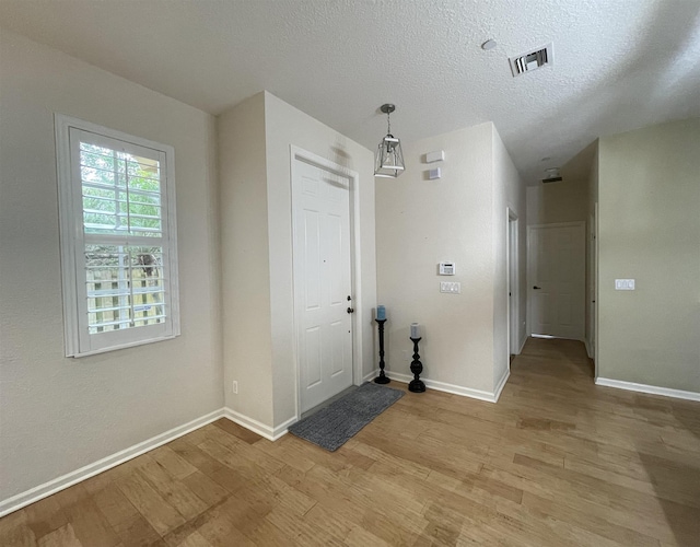 328 SE Bloxham Way, Stuart, FL 34997 - entrance foyer featuring light wood-style flooring, baseboards, and a textured ceiling