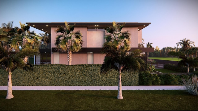 back house at dusk featuring a lawn