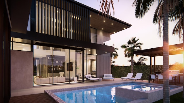 pool at dusk featuring a patio area and an in ground hot tub