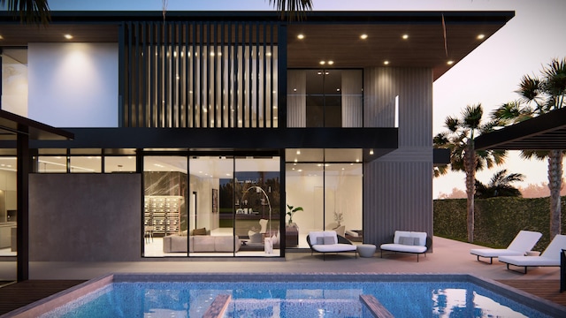 back house at dusk featuring a fenced in pool and a patio