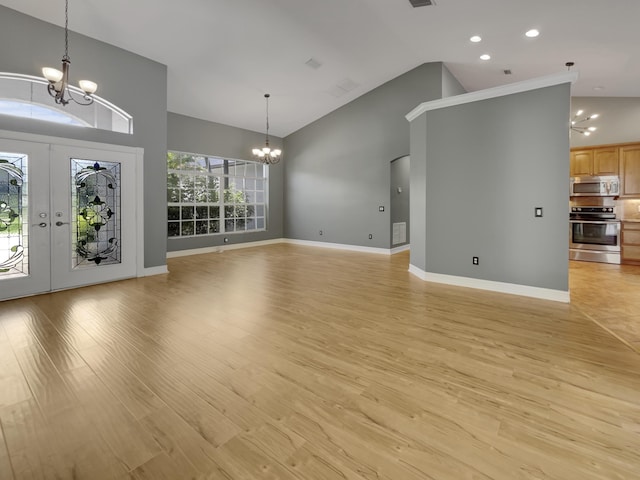 unfurnished living room featuring high vaulted ceiling, light hardwood / wood-style floors, an inviting chandelier, and french doors