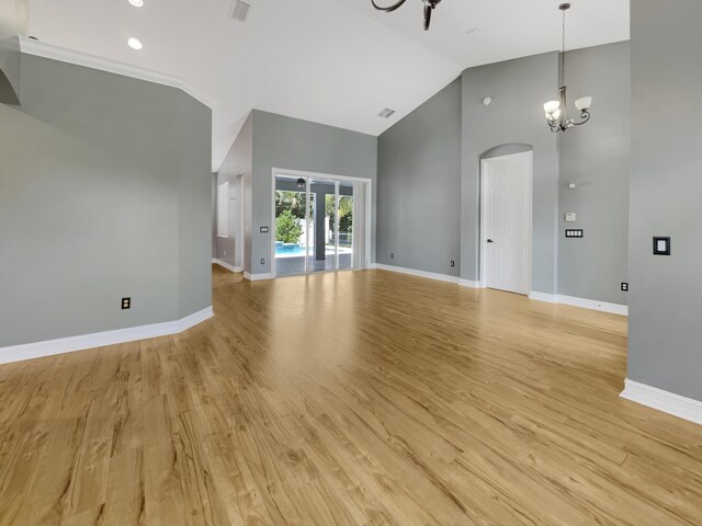 spare room featuring light hardwood / wood-style flooring, high vaulted ceiling, and a chandelier