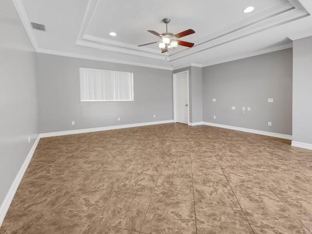 tiled empty room featuring ceiling fan, a tray ceiling, and ornamental molding