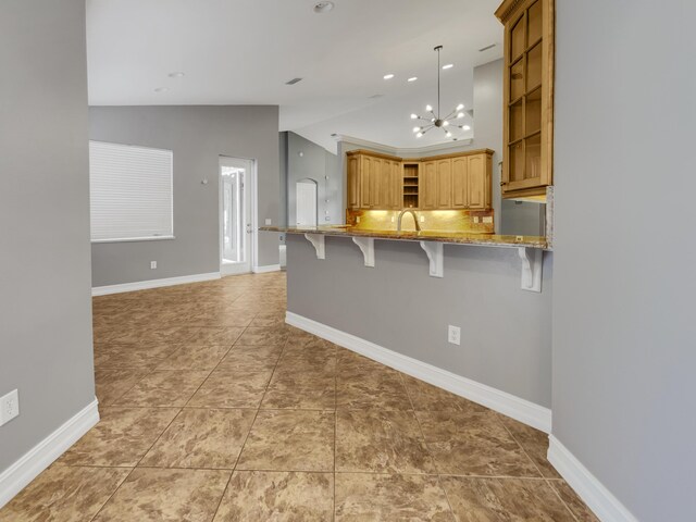 kitchen featuring light stone countertops, lofted ceiling, light tile patterned floors, kitchen peninsula, and hanging light fixtures