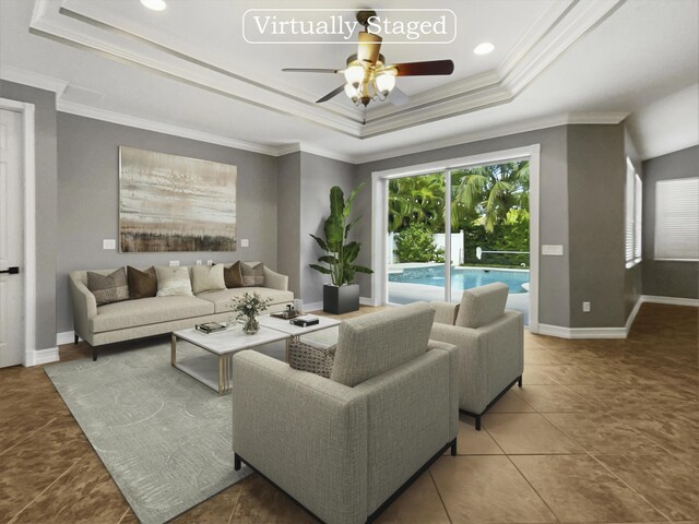 living room with ceiling fan, tile patterned flooring, a raised ceiling, and ornamental molding