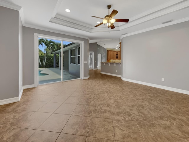 unfurnished living room featuring ceiling fan, light tile patterned floors, a tray ceiling, and ornamental molding