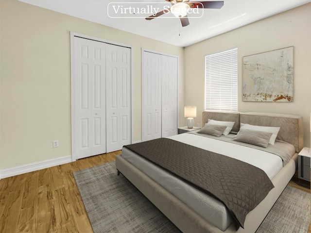 bedroom with ceiling fan, two closets, and wood-type flooring