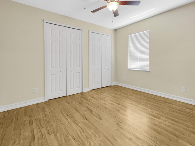 unfurnished bedroom with ceiling fan, two closets, and light hardwood / wood-style flooring