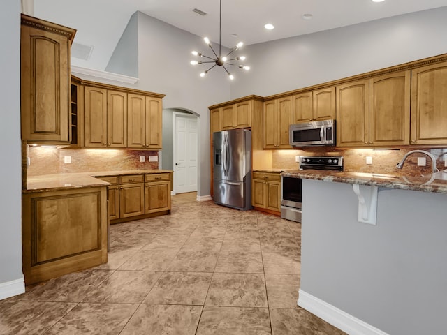 kitchen with stainless steel appliances, tasteful backsplash, light stone counters, light tile patterned flooring, and pendant lighting