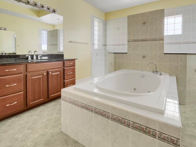 bathroom with tile patterned flooring, vanity, and a relaxing tiled tub