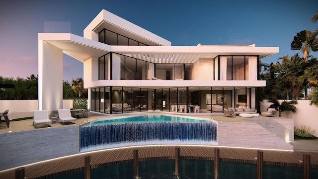 back house at dusk with pool water feature, an outdoor hangout area, and a patio