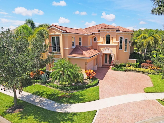 mediterranean / spanish-style house featuring decorative driveway, a tile roof, and stucco siding