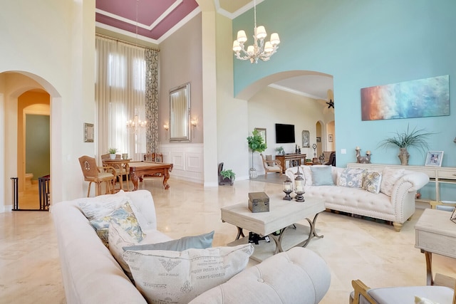 living room featuring a high ceiling, light tile patterned flooring, ornamental molding, and a chandelier