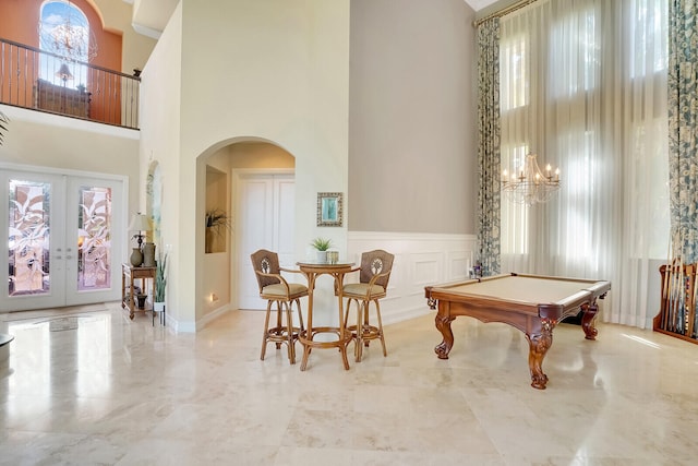 rec room featuring a notable chandelier, french doors, billiards, a towering ceiling, and tile patterned flooring