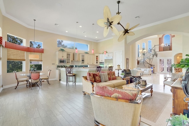 living room with ceiling fan, ornamental molding, and a towering ceiling