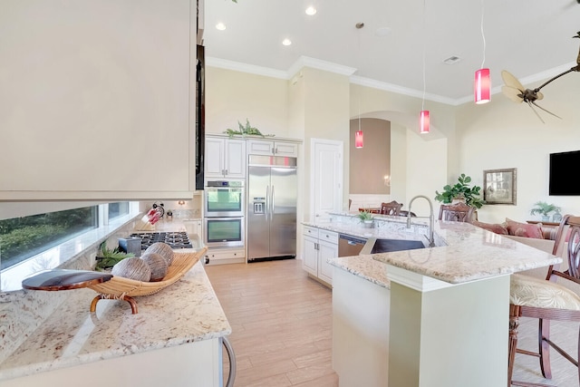 kitchen with stainless steel appliances, light hardwood / wood-style flooring, sink, light stone counters, and a kitchen breakfast bar