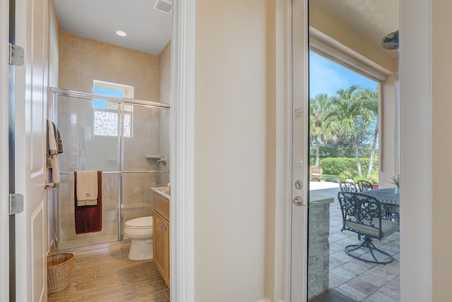 bathroom featuring an enclosed shower, vanity, a healthy amount of sunlight, and toilet