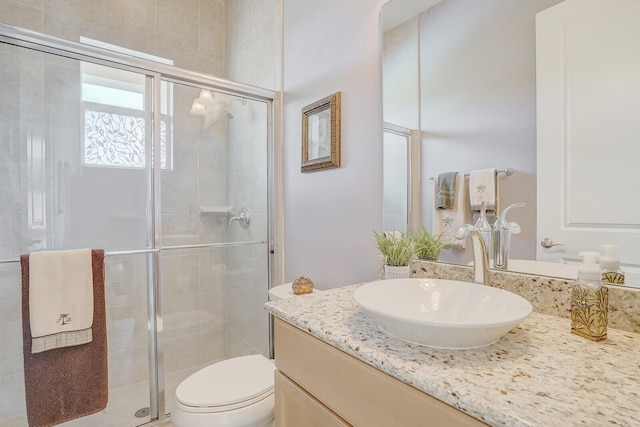 bathroom with a shower with door, vanity, and toilet