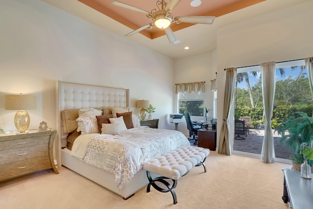 bedroom featuring ceiling fan, light carpet, access to exterior, and a high ceiling