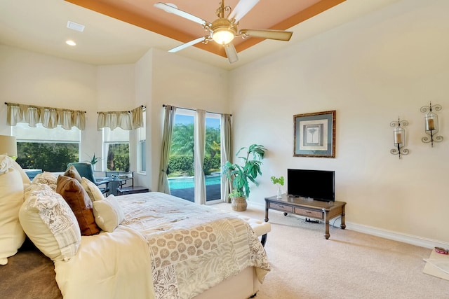 carpeted bedroom with ceiling fan, access to exterior, and a high ceiling