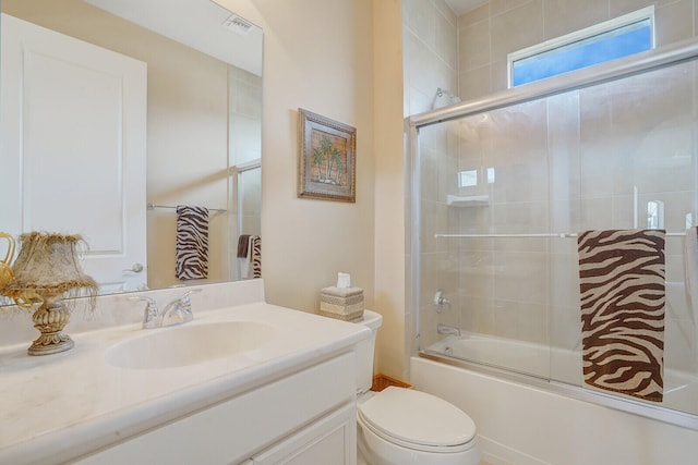 full bathroom with combined bath / shower with glass door, toilet, and vanity