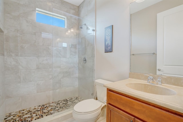 bathroom featuring vanity, tiled shower, and toilet