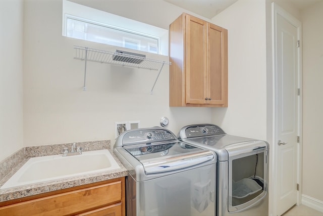 clothes washing area featuring sink, washing machine and clothes dryer, and cabinets