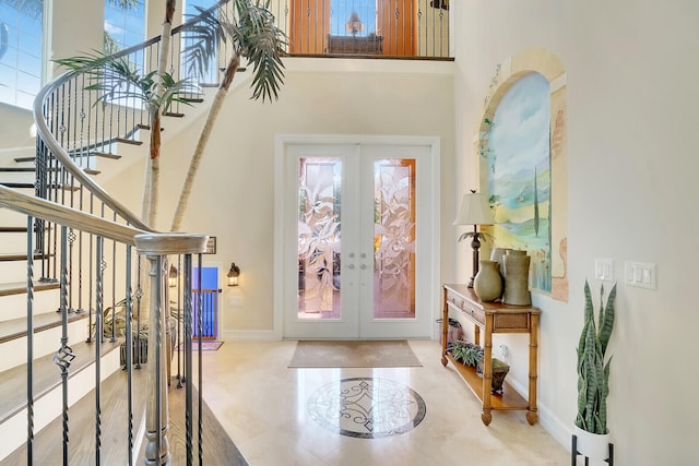 entryway with light tile patterned flooring, a towering ceiling, and french doors