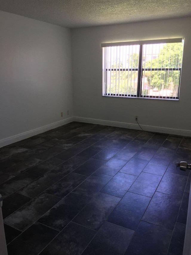 tiled spare room featuring a textured ceiling