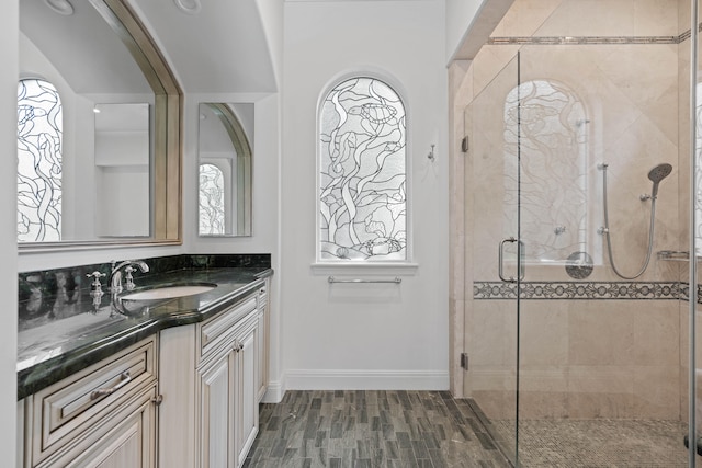 bathroom with hardwood / wood-style floors, plenty of natural light, a shower with door, and vanity