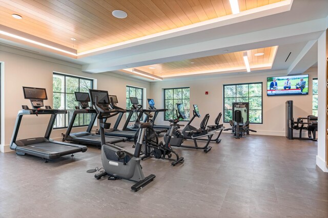 gym with a raised ceiling, a healthy amount of sunlight, and wooden ceiling