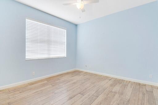 empty room with plenty of natural light, light hardwood / wood-style flooring, and ceiling fan