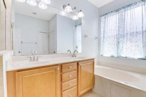 bathroom with a bath, tile patterned floors, and vanity