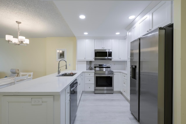 kitchen with sink, an inviting chandelier, decorative light fixtures, stainless steel appliances, and kitchen peninsula