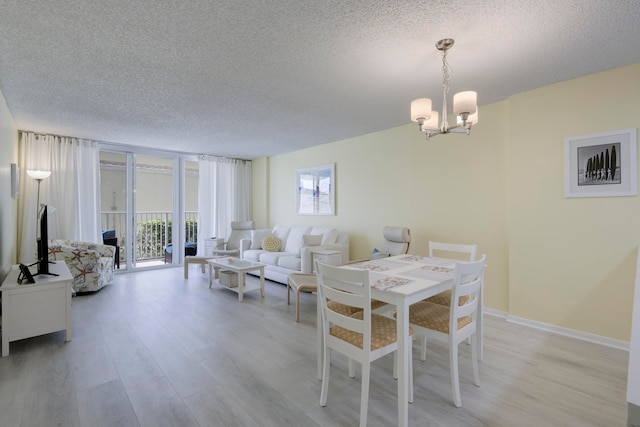 dining space with a textured ceiling, an inviting chandelier, and light hardwood / wood-style floors