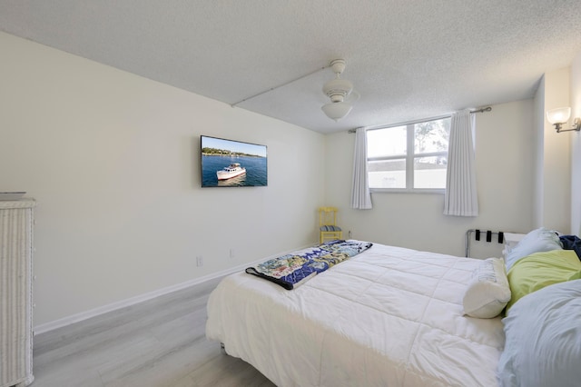 bedroom with a textured ceiling, ceiling fan, and wood-type flooring