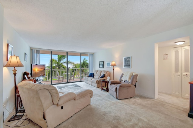 living room with a wall of windows, light colored carpet, and a textured ceiling